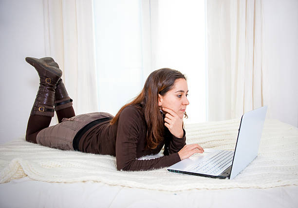 heureux cheveux bruns-femme travaillant sur son ordinateur portable - women computer home interior brown hair photos et images de collection