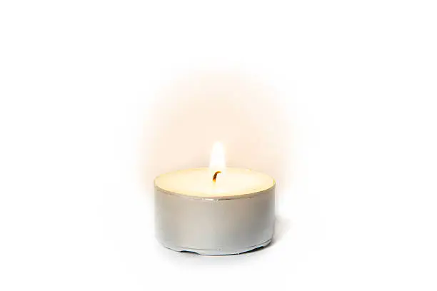 Shining flame on a tea light candle on white background