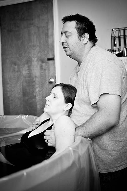 Husband Supporting Wife During Home Water Birth Black and white image of a loving husband supporting and coaching his wife through an intense home birth. water birth photos stock pictures, royalty-free photos & images