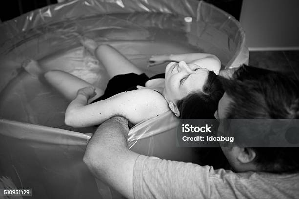 Husband Supporting Wife During Home Water Birth Stock Photo - Download Image Now - Labor - Childbirth, Childbirth, Water Birth