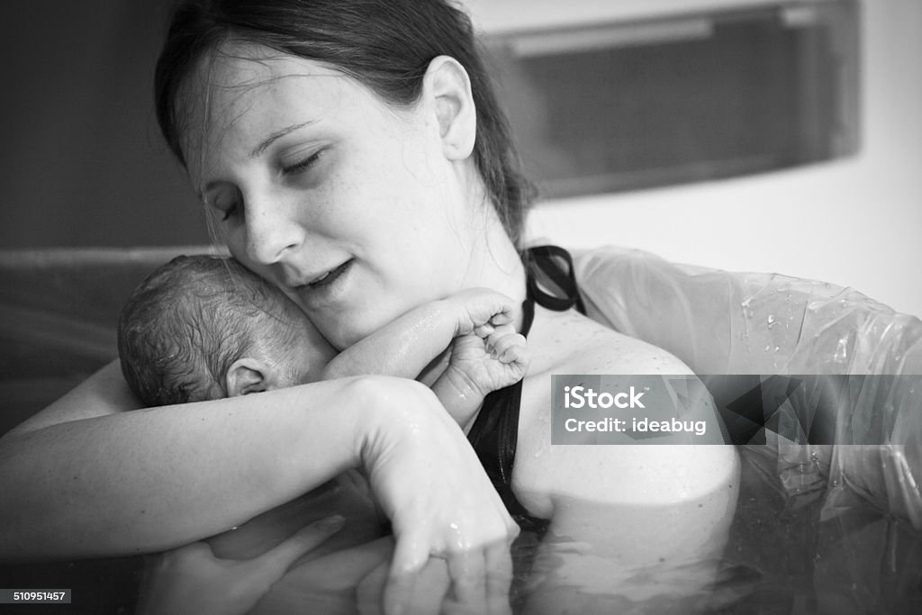 Mother Embracing Her Newborn after Home Water Birth Black and white image of a young mother embracing her newborn son after giving birth at home. Water Birth Stock Photo