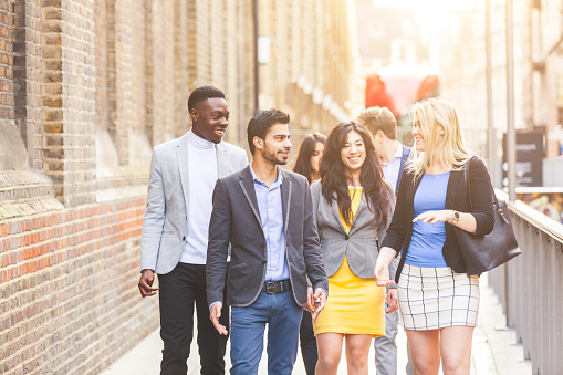 Business multiracial group walking in London. They all are young, smiling and wearing smart casual clothes. Mixed race group. Teamwork and business concepts.