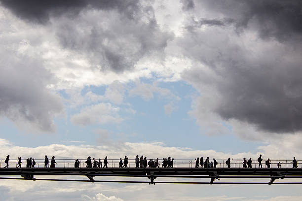 istock People crossing a bridge, over the Thames river 510954847