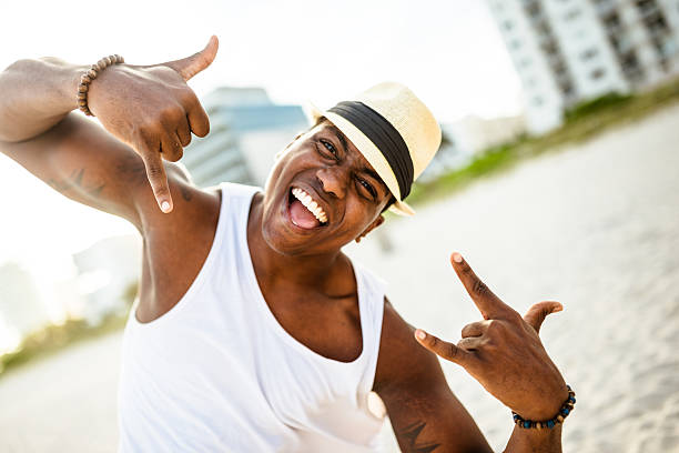 afrikanische mann tanzen am strand von miami - men latin american and hispanic ethnicity young men smiling stock-fotos und bilder