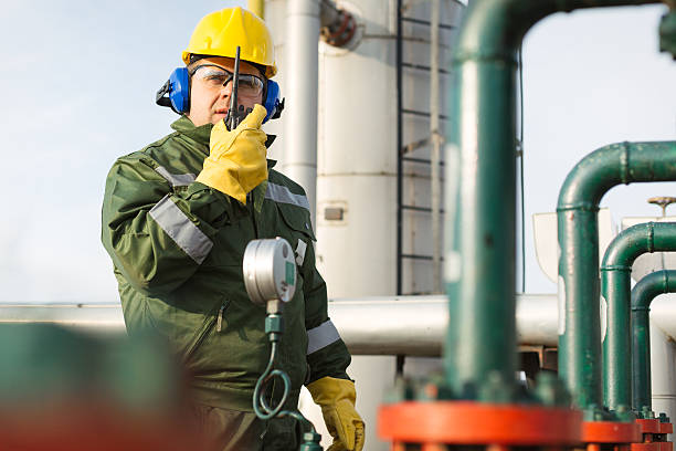 Gas Production Operator Worker with safety equipment on oil plant walkie talkie photos stock pictures, royalty-free photos & images