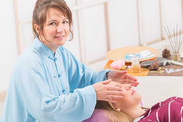 professionnels de reiki de guérison - reiki alternative therapy massaging women photos et images de collection