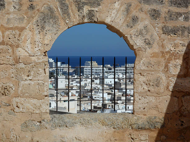 View overlooking the rooftops of buildings in old Sousse town, through an arch window in the Kasbah stone wall of the Medina, Tunisia.