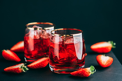 Red cocktail aperitif drink on ice with strawberries.
