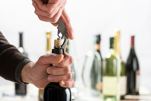 Opening bottle of wine with corkscrew