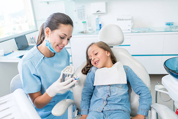 девушка у стоматолога учится чистить зубы - smiling dentist office dentists chair women стоковые фото и изображения
