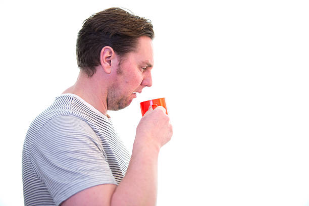 Man does not like his coffee/tea, white back ground Man does not like his coffee/tea, disgust, white back ground, side profile  gross coffee stock pictures, royalty-free photos & images