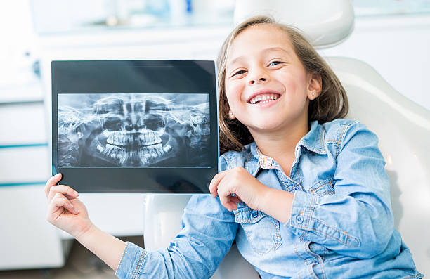 ragazza dal dentista in possesso di una radiografia - clinic dental equipment dental hygiene human teeth foto e immagini stock