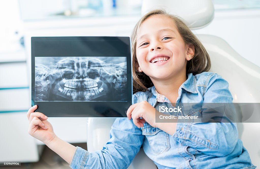 Girl at the dentist holding an x-ray Girl at the dentist holding and x-ray and looking at the camera smiling Child Stock Photo