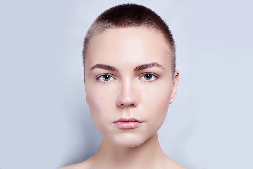 Beautiful Face of Young Woman bald, short hair with Clean Fresh Skin close up. Beauty Portrait. Beautiful Spa Woman Smiling. Perfect Fresh Skin. Pure Beauty Model. Youth and Skin Care Concept