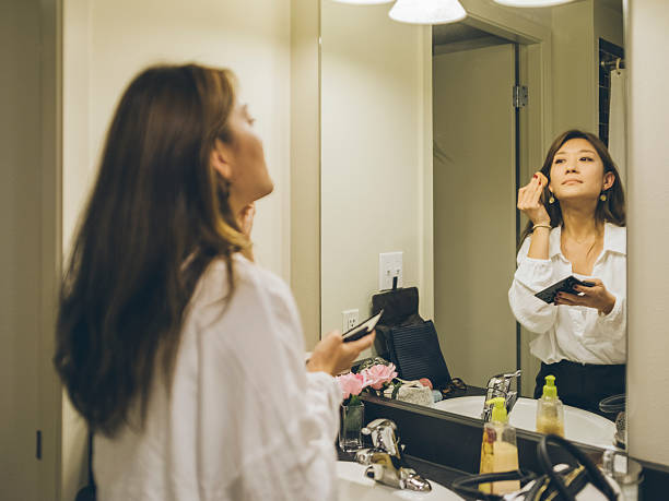 istock Young woman applying lipstick, looking in mirror 510970714