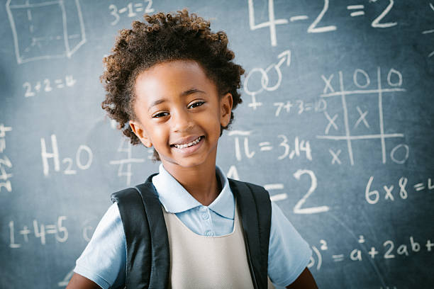 urocza prywatne szkoły przedszkola dziewczyna uśmiech przed tablica - african descent child brown eyes ethnicity zdjęcia i obrazy z banku zdjęć