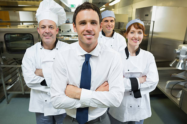 istock Young restaurant manager posing in front of team 510981595