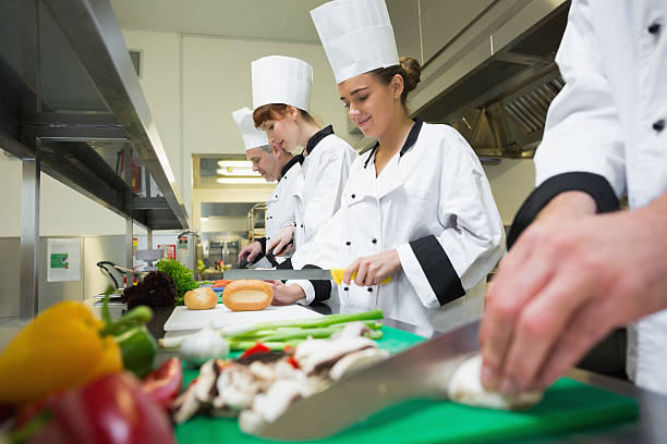 istock Four chefs preparing food at counter in a row 510994919