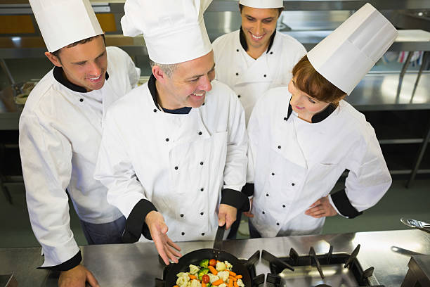 istock Experienced head chef showing pan to his colleagues 510995045