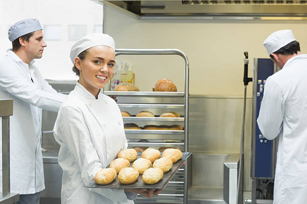 istock Cute young female baker holding a baking tray 510995715