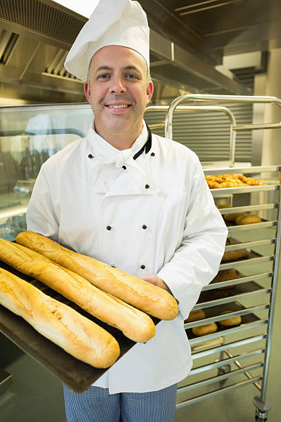 istock Mature baker presenting proudly some baguettes on a baking tray 510995721