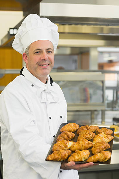 istock Baker showing some croissants on a baking tray 510998135