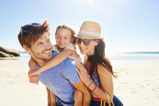 Cropped shot of a young one child family on a beach with the father giving his daughter a piggyback