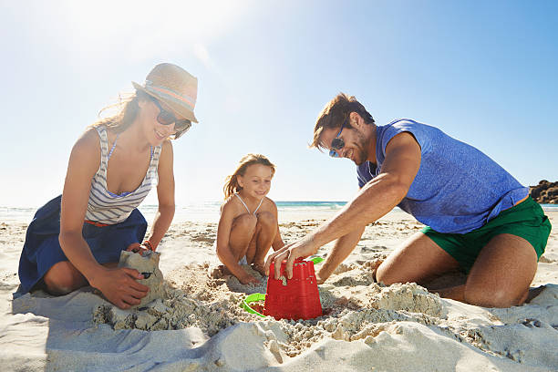 Let's see if we got it right Shot of a young family building a sandcastle on a beach sand castle stock pictures, royalty-free photos & images