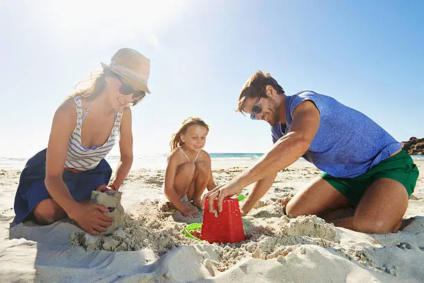 Shot of a young family building a sandcastle on a beach