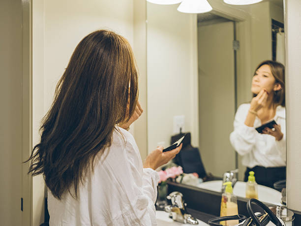 istock Young woman applying , looking in mirror 511010494