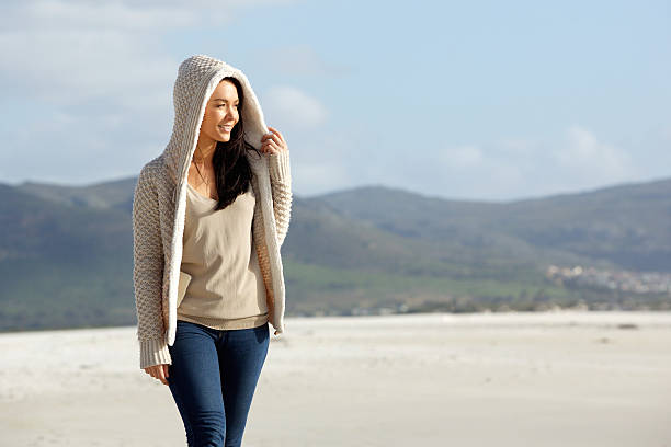 istock Young woman wearing a sweater walking at the beach 511010550