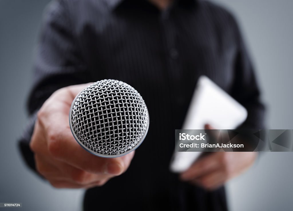 Interview with microphone Hand holding a microphone conducting a business interview or press conference Interview - Event Stock Photo