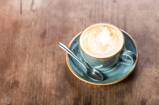 Cup of cappuccino coffee isolated on wooden background