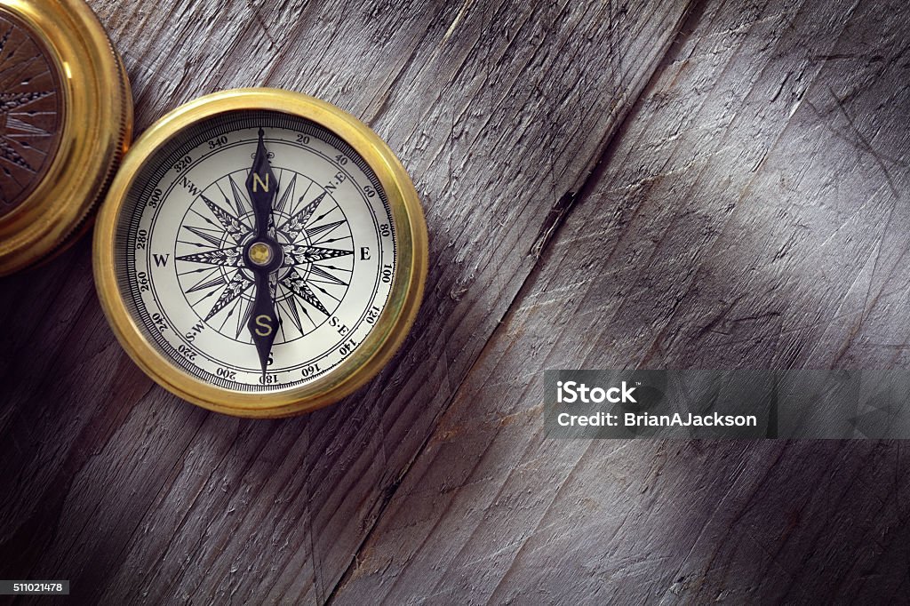 Antique golden compass Antique golden compass on wood background concept for direction, travel, guidance or assistance Navigational Compass Stock Photo
