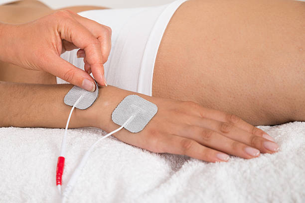 istock Therapist Placing Electrodes On Woman's Hand 511024398