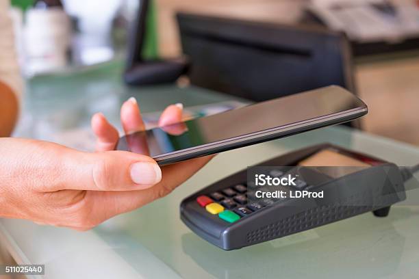 Woman Paying With Nfc Technology On Mobile Phone At Beautician Stock Photo - Download Image Now