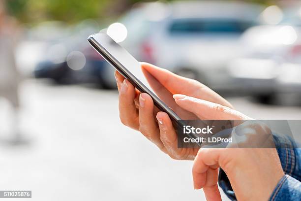 Woman Looking For Car With Mobile Phone In Parking Lot Stock Photo - Download Image Now