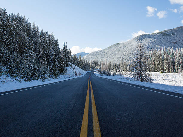 Fresh Snow Along Open Mountain Road An open mountain road after a fresh dusting of spring time snow.  Big Cottonwood Canyon, Utah 2014 middle of the road stock pictures, royalty-free photos & images