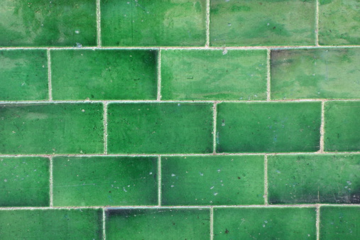 Section of wall made of shiny green rectangular tiles