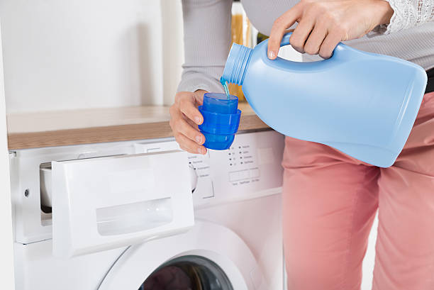 Close-up Of Female Hands Pouring Detergent In The Blue Bottle Cap