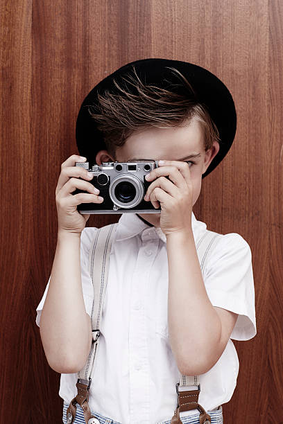 istock Young boy taking photograph with old camera 511028673