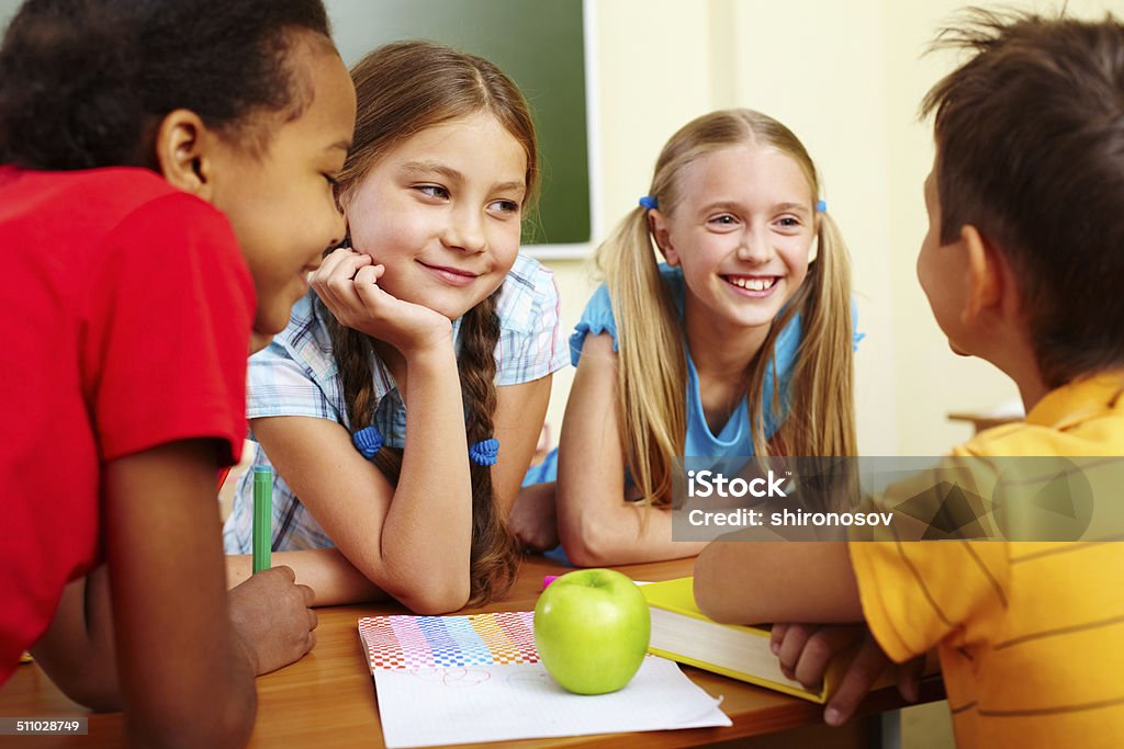 Classmates chatting Portrait of joyful schoolchildren chatting in classroom Adult Stock Photo