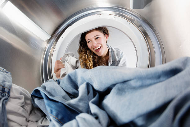 istock Seen from inside drum, pretty woman loading clothes dryer 511028929