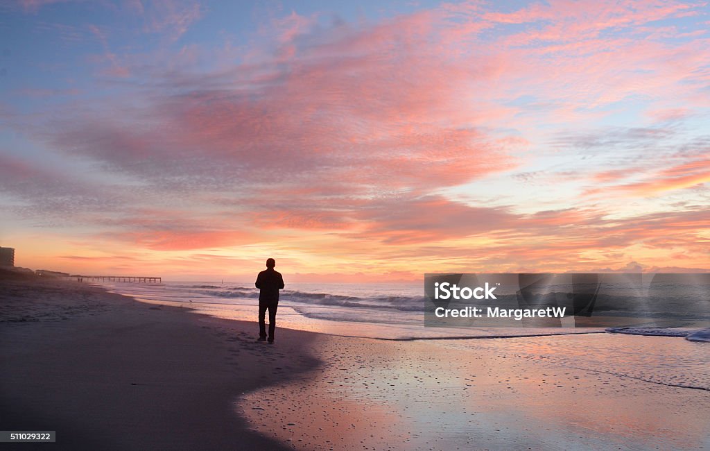 Man relaxing on the beach at sunrise. Man walking on the beautiful  beach at sunrise. Atlantic Beach, North Carolina. Beach Stock Photo