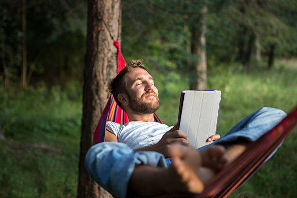 Serene man on hammock with digital tablet http://www.mediafire.com/convkey/6d6b/7mean2vh9anb8s3fg.jpg hammock men lying down digital tablet stock pictures, royalty-free photos & images