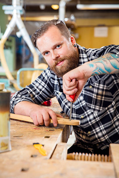 istock Smiling craftsman files wooden guitar neck in workshop 511031174