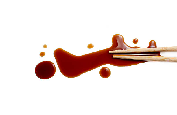splashes of soy sauce and chopsticks isolated on white wooden chopsticks dipped in soy sauce spilled. splashes and drops of isolated on white background. flat lay, top view soy sauce photos stock pictures, royalty-free photos & images