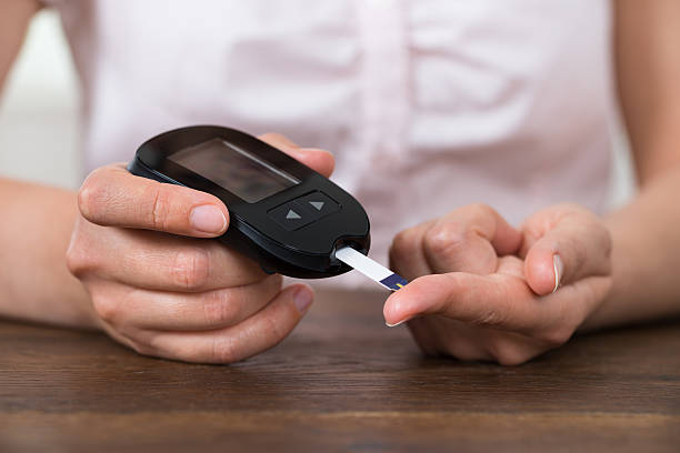 person hands holding glucometer - glükomere stok fotoğraflar ve resimler