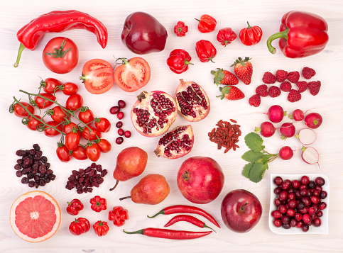 Red fruit and vegetables on white table, top view