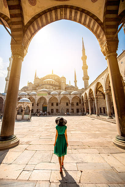 Woman near the Blue Mosque in Istanbul Young woman traveler in the green dress and hat walking to the Blue Mosque in Istanbul istanbul stock pictures, royalty-free photos & images